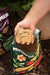 Hand scooping granular organic fertilizer from a Mindful Farm bag for healthy plants. Worm castings bag visible.
