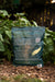 Organic Feather Meal fertilizer bag with nutrient details and feather logo, standing in a lush garden bed.
