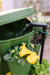 Water flowing into a GreenStalk self-watering vertical garden planter with herbs, yellow pansies, and parsley.