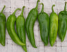 Seven fresh green chili peppers on a textured white cloth. Perfect for cooking, recipes, or gardening.