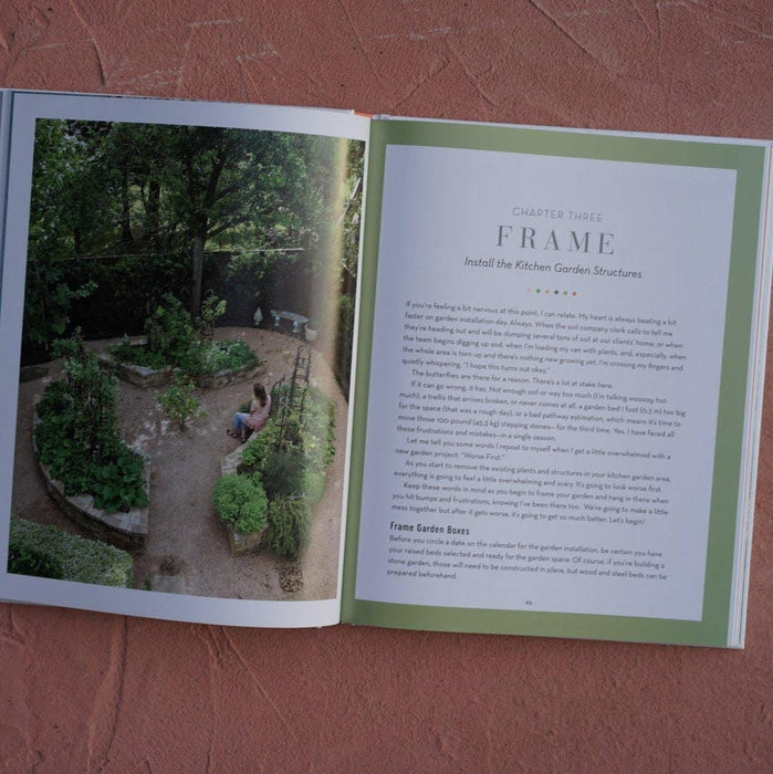 Open gardening book. Left: kitchen garden photo with raised beds, person. Right: "Install the Kitchen Garden Structures" text.
