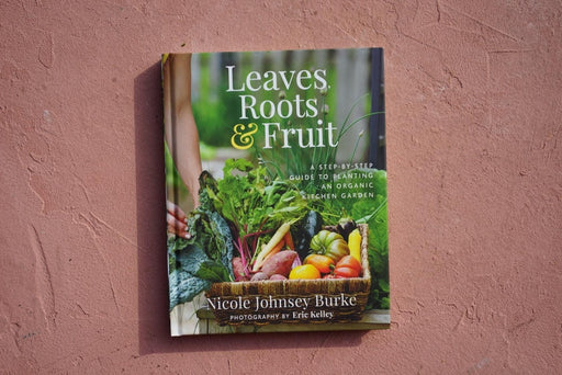 "Leaves, Roots & Fruit" organic gardening book. Cover shows person harvesting fresh vegetables: kale, carrots, tomatoes.