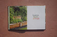 Open gardening book "Leaves, Roots & Fruit" showing a vibrant raised garden bed with lush edible plants.
