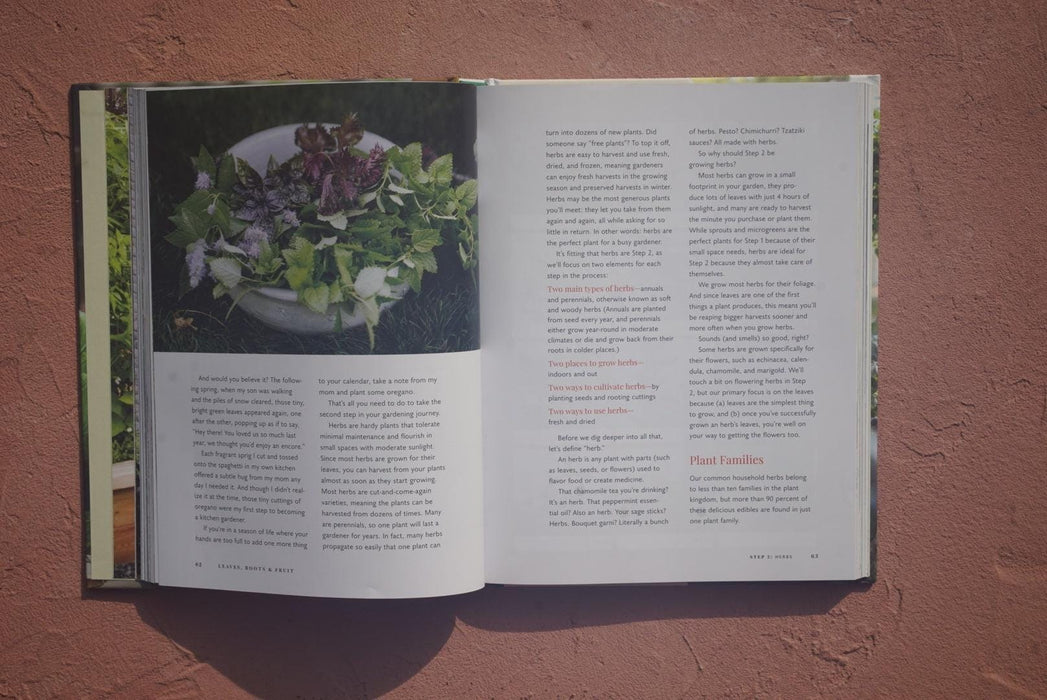 Open book with a guide to growing herbs, featuring a close-up of mixed fresh green and purple herbs in a pot.