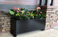 Modern black metal planter on wheels with pink anthurium flowers & green foliage for patio decor.