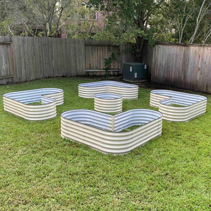 Five beige corrugated steel raised garden beds in unique shapes on a green backyard lawn. Great for planting vegetables/flowers.
