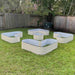 Five beige corrugated steel raised garden beds in unique shapes on a green backyard lawn. Great for planting vegetables/flowers.