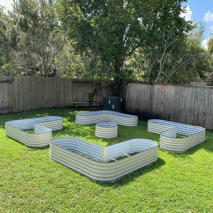 Backyard with galvanized metal raised garden beds in L-shapes, rectangles, and circles on green grass. Ideal for planting.
