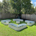 Backyard with galvanized metal raised garden beds in L-shapes, rectangles, and circles on green grass. Ideal for planting.