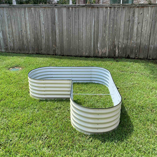 L-shaped galvanized steel raised garden bed on green grass. Durable corrugated metal planter for backyard gardening.