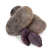 Whole and halved purple potatoes revealing vibrant deep purple flesh. Fresh produce, healthy vegetables.