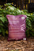 Purple bag of organic vermicompost worm castings for healthy garden plants, sitting on mulch.