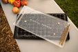 Mindful Farmer seed sower on a soil-filled propagation tray with tiny seeds. Fresh heirloom tomatoes await planting.