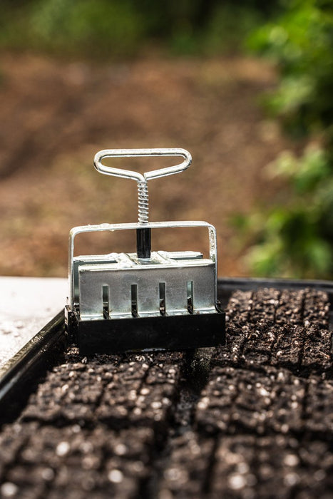 Silver soil block maker creating seed starting blocks in a tray. Essential organic gardening and plant propagation tool.