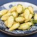 Fresh white pineberries with green caps in a blue and white patterned ceramic bowl.