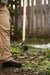 Gardener uses a long-handled weeding tool to pull weeds with roots from garden soil. Effective weed removal.