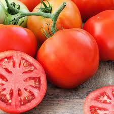 Fresh ripe red tomatoes, whole and sliced, with green stems on a wooden background. Healthy garden produce.