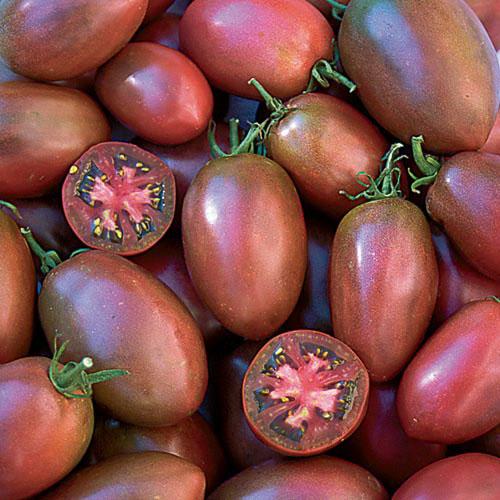 Dark red heirloom plum tomatoes, whole and sliced, revealing juicy interior.