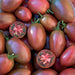 Dark red heirloom plum tomatoes, whole and sliced, revealing juicy interior.