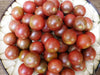 Ripe reddish-brown cherry tomatoes on a white decorative plate. Freshly harvested heirloom vegetables for healthy cooking.