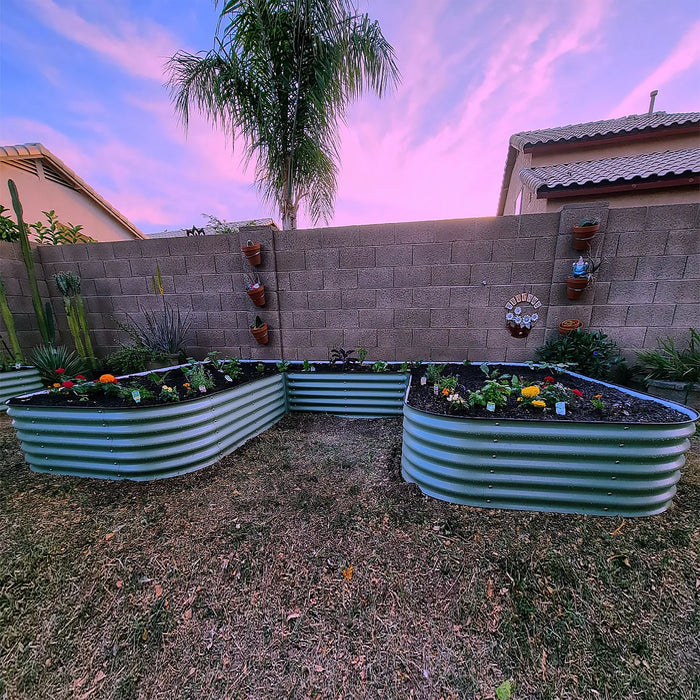 Corrugated metal raised garden beds with herbs, flowers, and vegetables in a backyard desert landscape with a pink sunset.