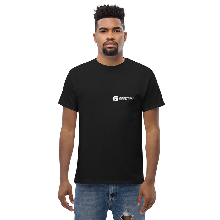 Man wearing black Seedtime t-shirt, casual streetwear, ripped denim jeans. Men's apparel.