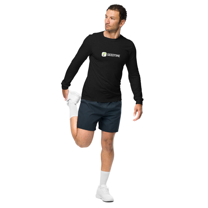Man in black Seedtime long-sleeve shirt & dark shorts stretching quad. Activewear, fitness, workout gear.