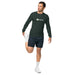 Man in Seedtime dark green long-sleeve shirt and navy shorts stretching. Athletic apparel for fitness.