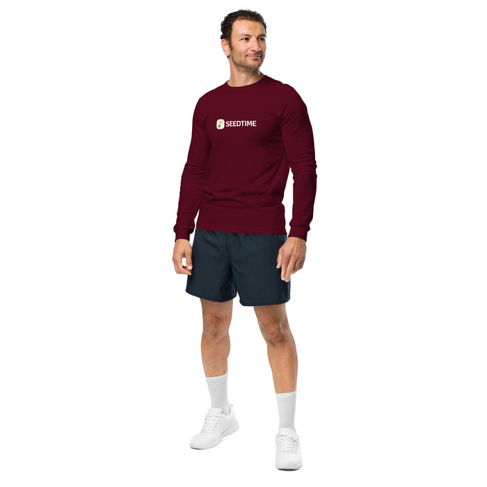 Man wearing a maroon Seedtime long-sleeve shirt, dark athletic shorts, and white sneakers.