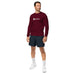 Man wearing a maroon Seedtime long-sleeve shirt, dark athletic shorts, and white sneakers.