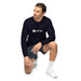Man in navy blue SEEDTIME long-sleeve shirt, dark shorts, and white sneakers, kneeling. Casual men's athletic wear.