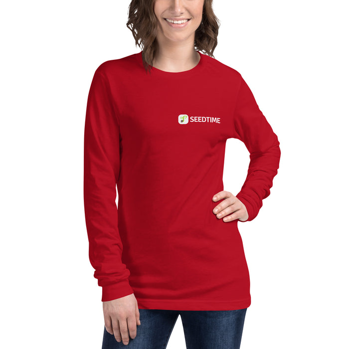 Smiling woman wearing a red long-sleeve Seedtime shirt with green sprout logo. Comfortable women's casual apparel.