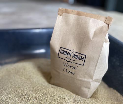 Urban Worm Company Worm Chow bag on bedding. Premium organic worm food for vermicomposting.