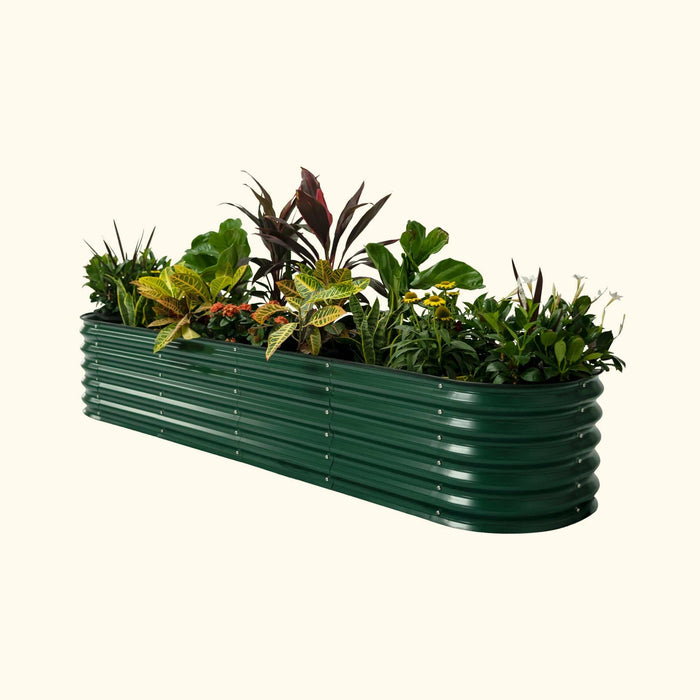 Dark green corrugated metal raised garden bed planter filled with diverse plants, colorful foliage, and small flowers.