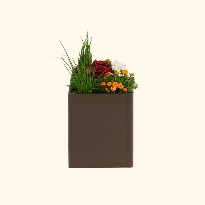 Dark brown rectangular planter with a vibrant mix of pink, orange, white flowers, tall grass, and evergreen foliage.