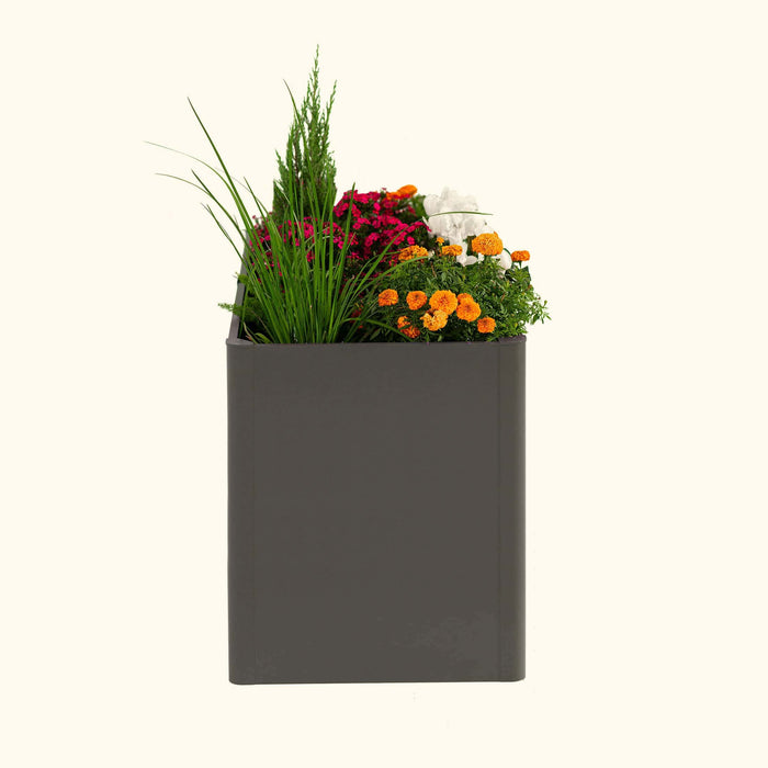 Modern dark grey rectangular planter filled with vibrant pink, orange, white flowers, and green ornamental grasses.