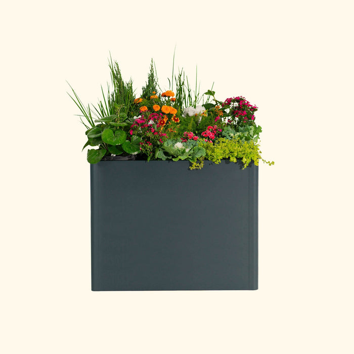 Stylish dark grey outdoor planter with vibrant orange, pink, and white flowers, lush green foliage, and trailing plants.