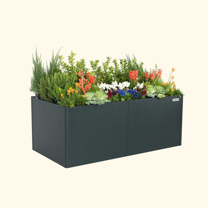 Modern charcoal planter box by Vego Garden, filled with colorful flowers, evergreen shrubs, and lush green plants.