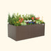 Brown Vego Garden metal raised planter box with vibrant flowers, lush green plants, and evergreens.