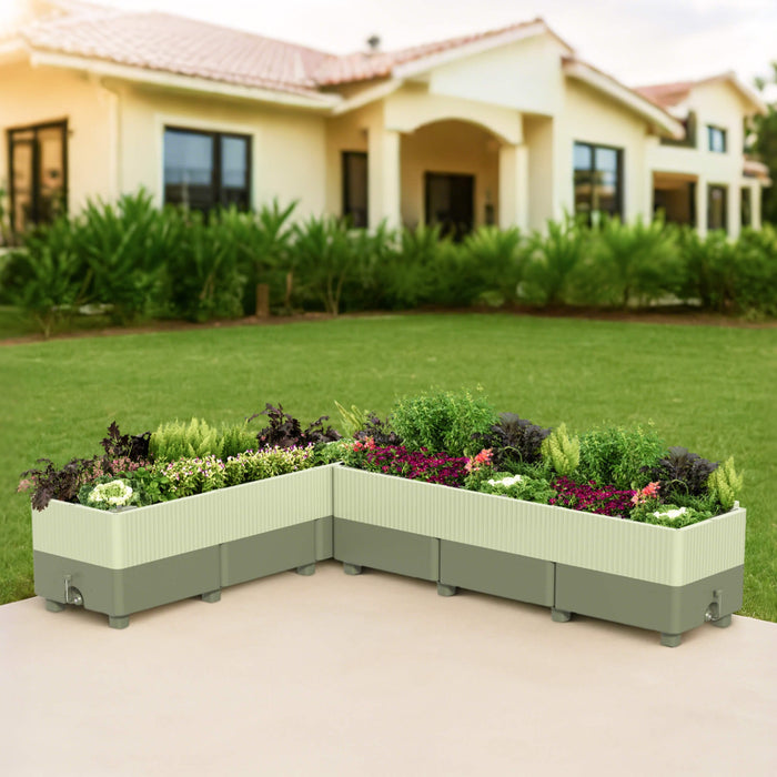L-shaped sage green self-watering raised garden bed filled with herbs, flowers, and leafy greens on a patio.
