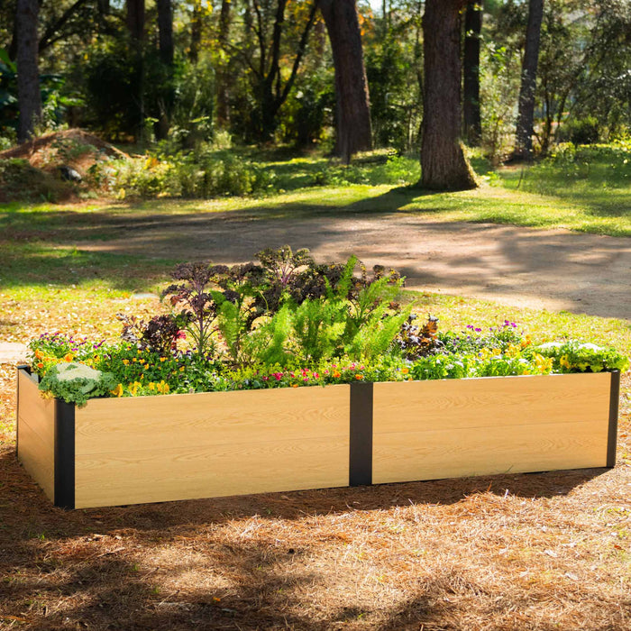 Modern light wood-look raised garden bed with dark posts, vibrant flowers, kale, and lush green plants in a sunny garden.