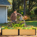 Man watering a composite raised garden bed filled with colorful flowers and leafy greens in a sunny backyard garden.