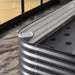 Dark gray corrugated metal raised garden bed corner with self-watering wicking system and ground cover. Ideal for gardening.