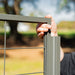 Hand installing gray metal wire mesh fence panel into a post. Outdoor garden fence construction.