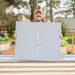 Smiling man holds Vego Garden textured panel for a beige corrugated metal raised garden bed in a backyard.