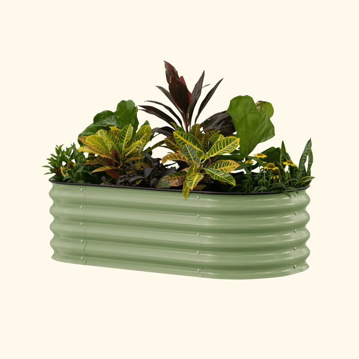 Sage green corrugated metal planter box overflowing with lush, colorful plants, including crotons, snake plants, and yellow flowers.