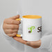 Hands hold white coffee mug with yellow handle, green seed sprout logo, and "SEED" text. Eco-friendly drinkware.