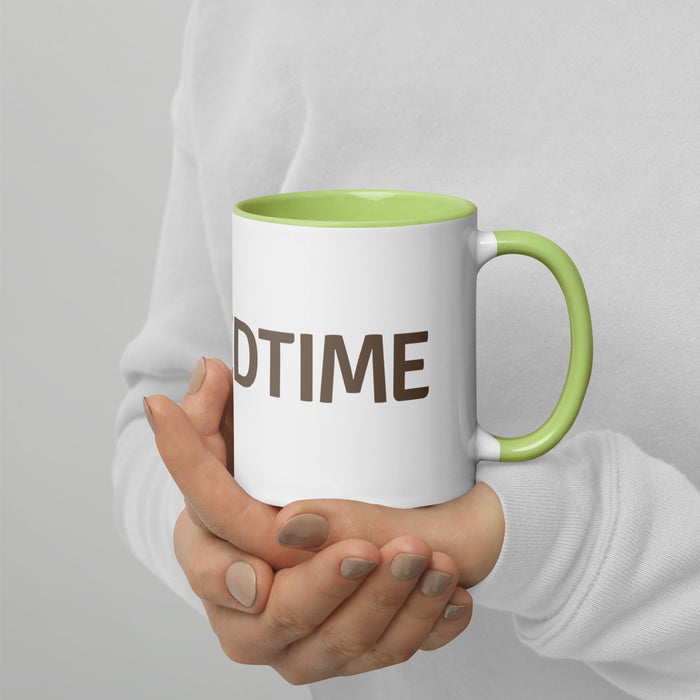 Hands hold white 'BEDTIME' mug with green rim and handle. Cozy coffee or tea cup.