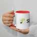 Hands hold a white ceramic coffee mug with red handle & interior. Features a green sprouting seed logo and partial 'SE' text.