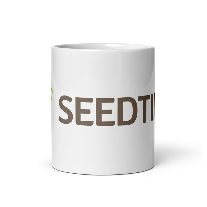 White ceramic mug featuring brown "SEEDT" text and a green leaf logo.